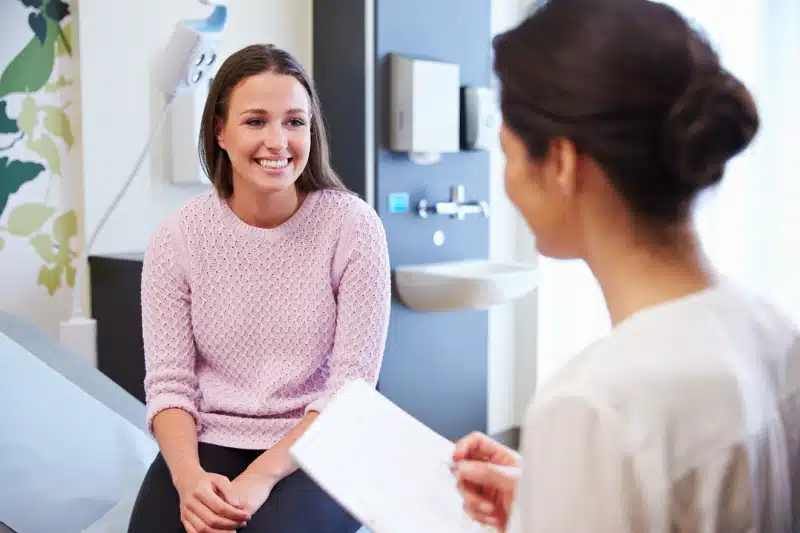 Woman in pink jumper talking to GP