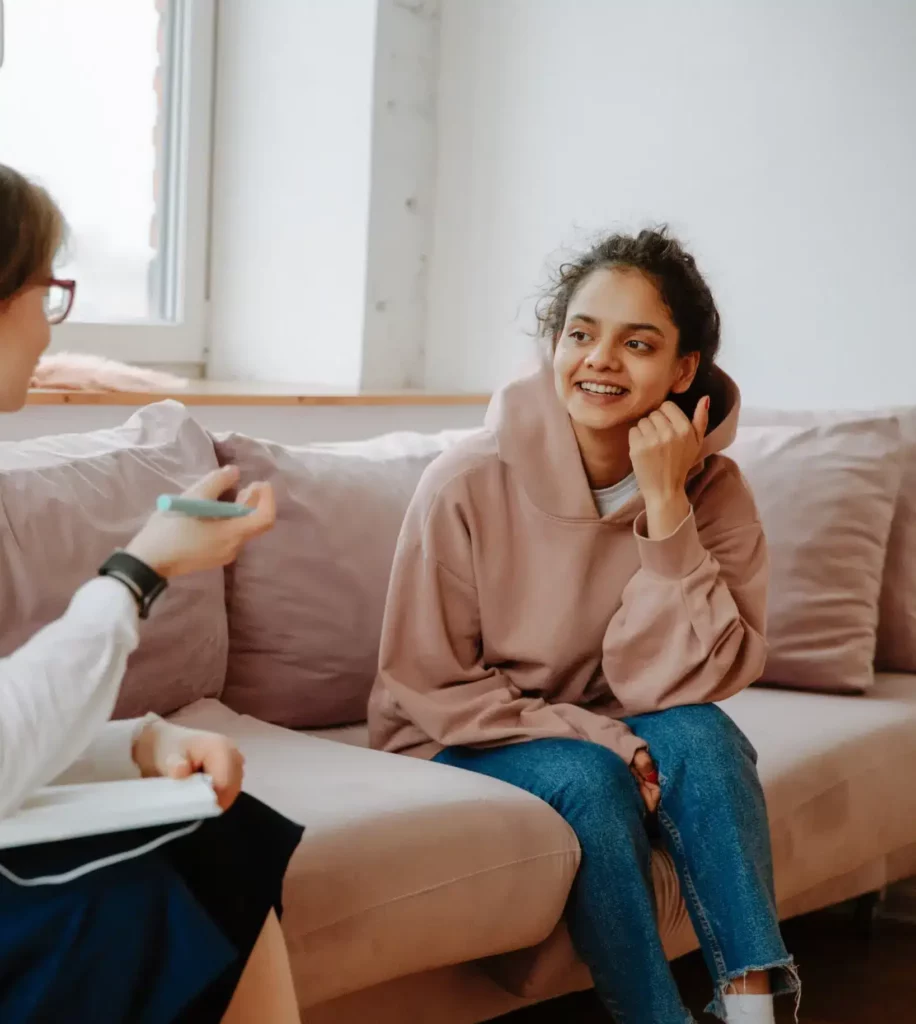 two women chatting side by side on sofa